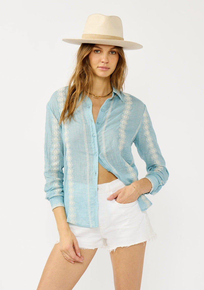 [Color: Light Blue/Ivory] A front facing image of a blonde model wearing a light blue shirt with an embroidered stripe pattern,  a classic collar neckline, and button front. A boho inspired shirt for festivals, casual outings, and country events. 