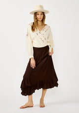 [Color: Vanilla/Rust] A front facing image of a blonde model wearing an off white embroidered wrap top with dropped shoulders, long sleeves, and a side tie closure. An effortless boho top for the fall season. 