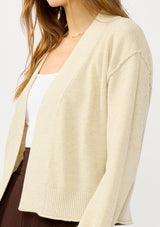[Color: Heather Natural] A detail image of a blonde model wearing a casual, lightweight cardigan with an open front, ribbed trim, and rolled edges. A classic staple cardigan for transitional styling. 