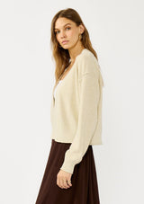 [Color: Heather Natural] A side facing image of a blonde model wearing a casual, lightweight cardigan with an open front, ribbed trim, and rolled edges. A classic staple cardigan for transitional styling. 