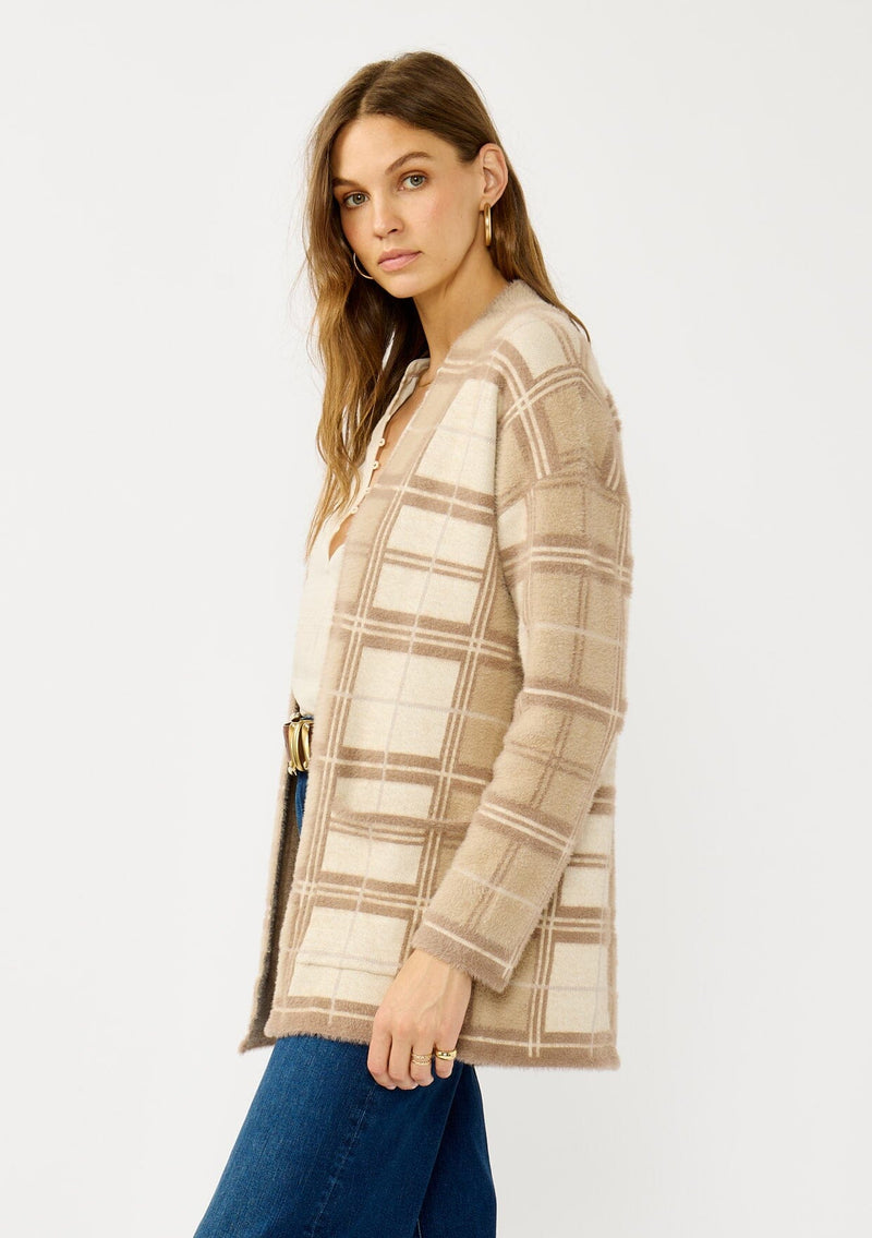 [Color: Tan/Mocha] A side facing image of a blonde model wearing a brown plaid cardigan with cozy long sleeves and an open front. A warm fuzzy sweater for the fall season. 