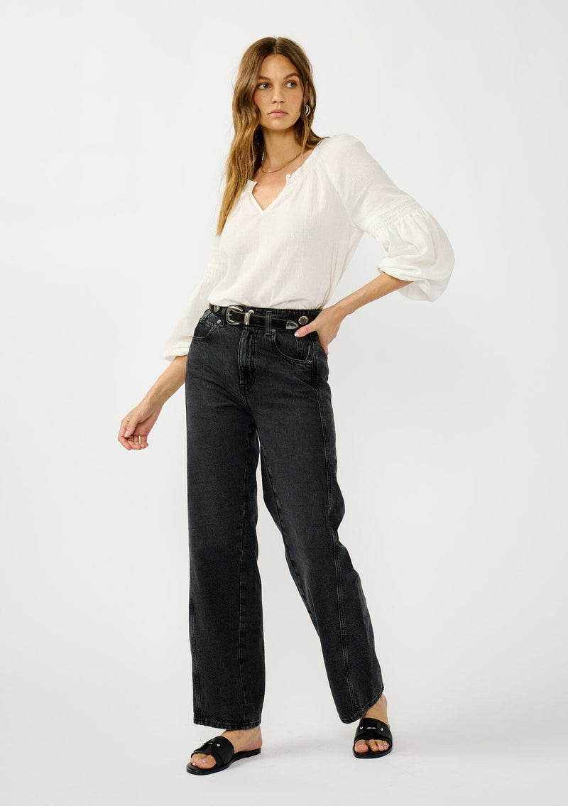 [Color: White] A front facing image of a blonde model wearing a white crinkled cotton blouse with long bishop sleeves, shirred detail along the sleeves, a split v-neckline with button closure. A year round staple for any season. 