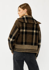 [Color: Brown/Taupe] A back facing image of a blonde model wearing a fall season black and brown plaid jacket with a zip up front and side pockets. 