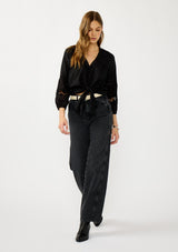 [Color: Black] A front facing image of a blonde model wearing a black lightweight cotton-blend top with a tie front detail, button front, and 3/4 length sleeves with embroidered and cutout details. 