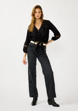 [Color: Black] A front facing image of a blonde model wearing a black lightweight cotton-blend top with a tie front detail, button front, and 3/4 length sleeves with embroidered and cutout details. 