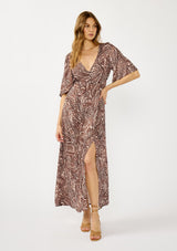 [Color: Natural/Brown] A front facing image of a blonde model wearing a brown paisley maxi dress with a deep v-neckline, flowy short sleeves, twist front, and a side slit. A fall bohemian maxi dress for special occasions. 