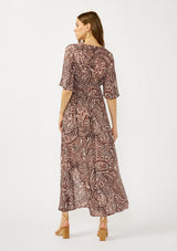 [Color: Natural/Brown] A back facing image of a blonde model wearing a brown paisley maxi dress with a deep v-neckline, flowy short sleeves, twist front, and a side slit. A fall bohemian maxi dress for special occasions. 