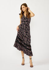 [Color: Black/Pink] A front facing image of a blonde model wearing a black and pink floral print maxi dress with flutter cap sleeves, a v-neckline, button front, smocked back, and sheer tiered layers. A special occasion dress for the fall season. 