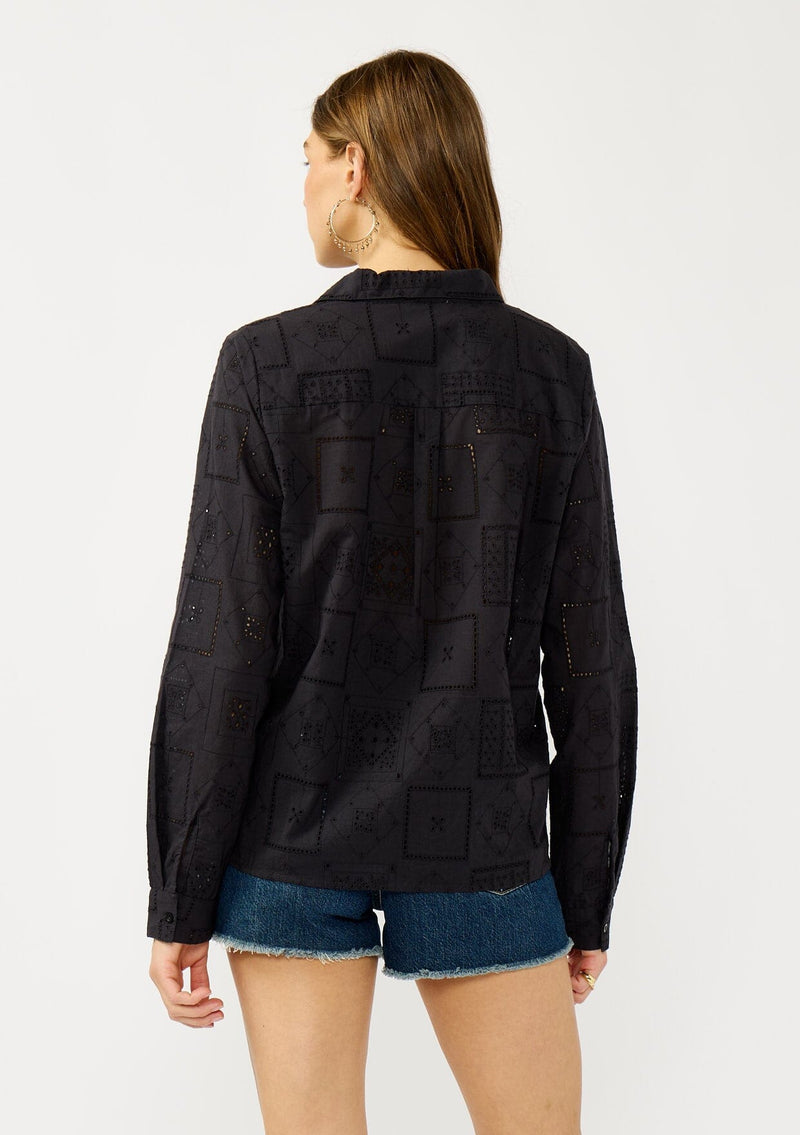 [Color: Graphite] A back facing image of a blonde model wearing a black eyelet shirt with a collared neckline, button front, and button cuff closure.