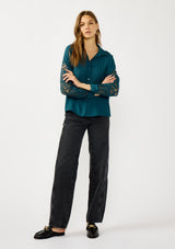 [Color: Teal] A front facing image of a blonde model wearing a striped jacquard teal shirt with lace cutouts, a button front, and collared neckline. A cool and polished blouse for the fall season. 