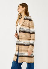 [Color: Camel/Brown] A side facing image of a blonde model wearing a brown and tan striped mid length coatigan with a shawl collar, button front, and side patch pockets. Effortlessly cozy for the fall and winter season. 