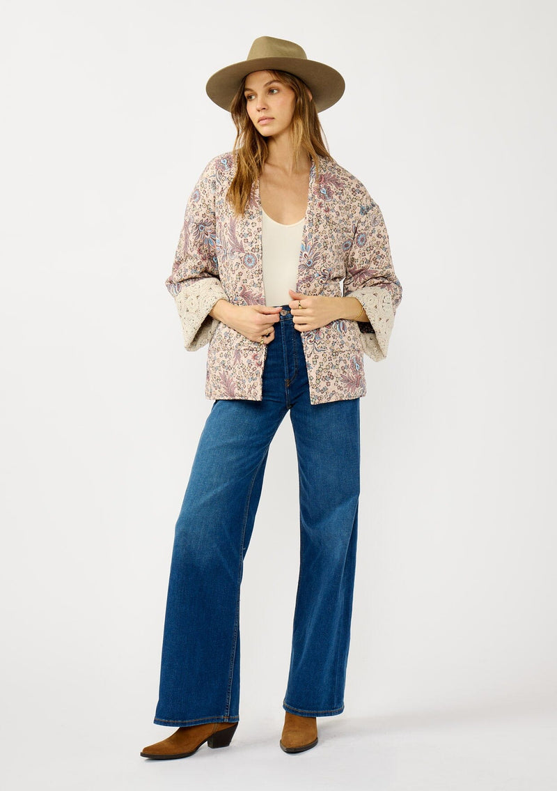 [Color: Mauve/Natural] A front facing image of a blonde model wearing a mauve pink floral bohemian jacket with an oversized fit, long sleeves, crochet trim, and side pockets. 