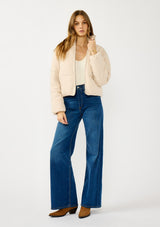 [Color: Natural] A front facing image of a blonde model wearing a light beige soft knit puffer jacket with a zipper front, high collar, and side pockets. A classic fall jacket for cold weather. 