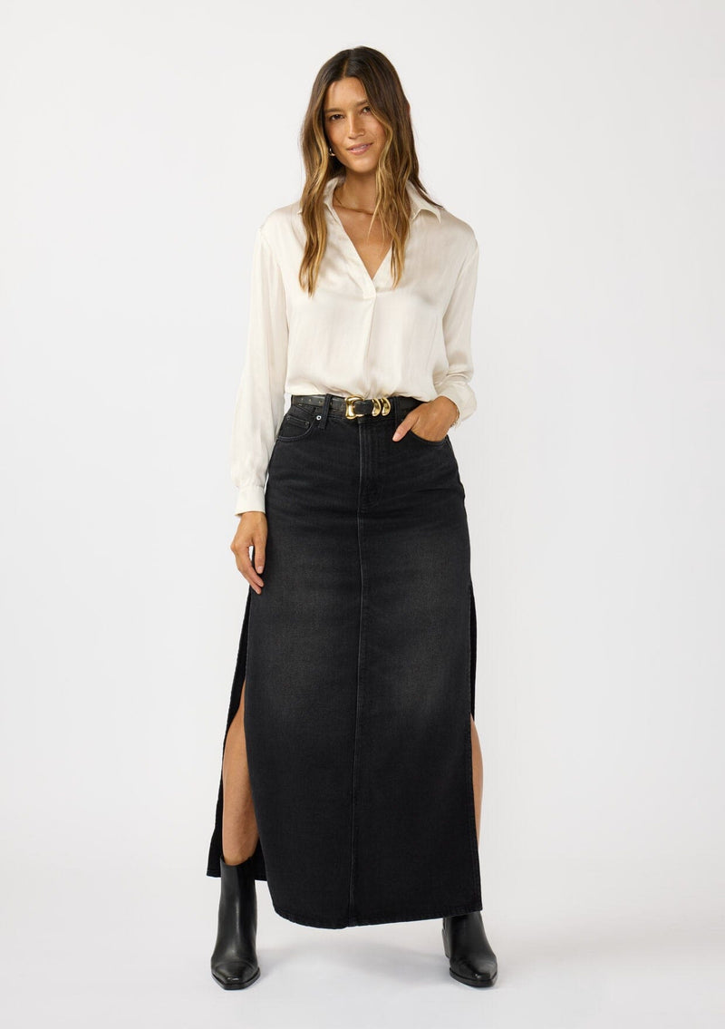 [Color: Eggshell] A front facing image of a brunette model wearing an ivory silky poly satin blouse with a split v-neckline, collar, and long sleeves with button cuffs. 