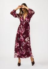 [Color: Wine/Dusty Rose] A front facing image of a brunette model wearing a burgundy floral maxi dress with an empire waist with drawstring, long sleeves, and a deep v-neckline. An elegant dress for the holidays or other special occasions. 