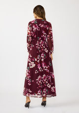 [Color: Wine/Dusty Rose] A back facing image of a brunette model wearing a burgundy floral maxi dress with an empire waist with drawstring, long sleeves, and a deep v-neckline. An elegant dress for the holidays or other special occasions. 