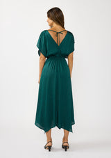 [Color: Emerald] A front facing image of a brunette model wearing a formal holiday party dress with sparkly metallic stripe details. Featuring a surplice v-neckline, short dolman sleeves, an elastic waist, open back with tie detail,  and an asymmetrical hemline. 