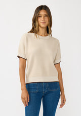 [Color: Heather Stone/Natural] A front facing image of a brunette model wearing a tan cozy knit short sleeve sweater top with a round neckline and contrast ribbed trims. 