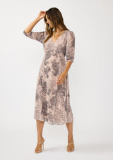 [Color: Natural/Brown] A front facing image of a brunette model wearing a nude brown floral midi dress with a v-neckline, 3/4 length sleeves, and a flattering empire waist. 