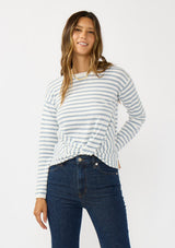 [Color: Ivory/Dusty Blue] A front facing image of a brunette model wearing a classic ivory and light blue striped knit pullover sweater. With long sleeves, a drop shoulder, a crew neckline, and a twist front detail at the waist. 