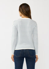 [Color: Ivory/Dusty Blue] A back facing image of a brunette model wearing a classic ivory and light blue striped knit pullover sweater. With long sleeves, a drop shoulder, a crew neckline, and a twist front detail at the waist. 