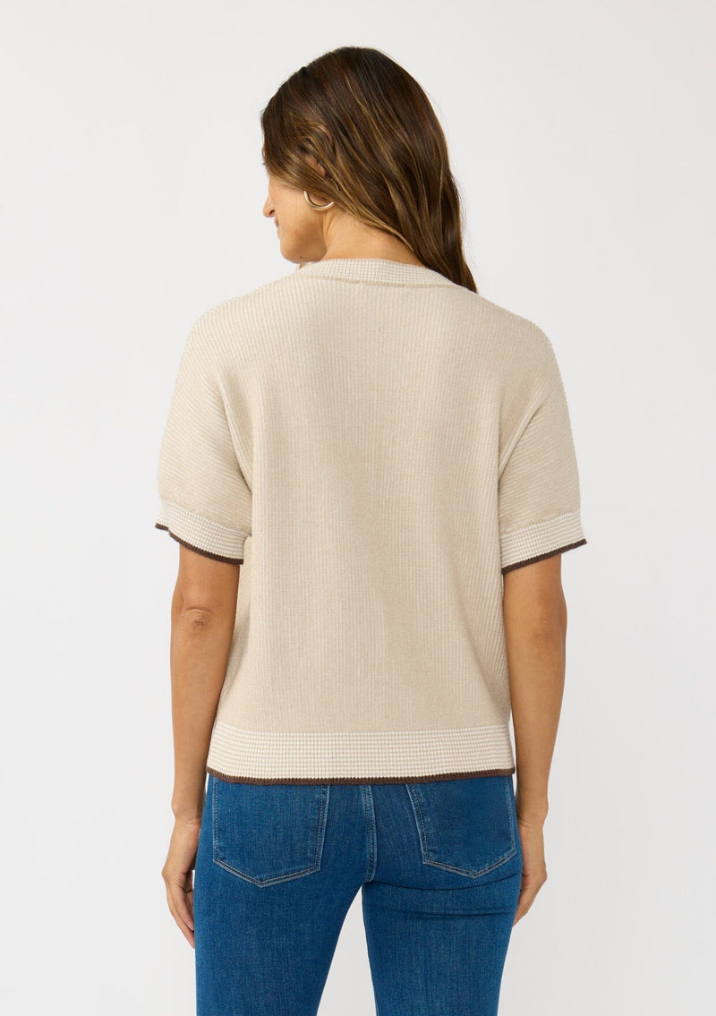 [Color: Heather Stone/Natural] A back facing image of a brunette model wearing a tan cozy knit short sleeve sweater top with a round neckline and contrast ribbed trims. 