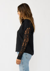 [Color: Black] A side facing image of a blonde model wearing a striped jacquard black shirt with lace cutouts, a button front, and collared neckline. A cool and polished blouse for the fall season. 