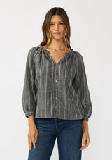 [Color: Charcoal] A front facing image of a brunette model wearing a dark grey striped blouse with long sleeves, a split v-neckline, and button front. 