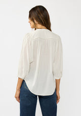 [Color: Cream/Black] A back facing image of a brunette model wearing a boho striped button front blouse with a pintuck yoke, lattice trim, and voluminous sleeves. 
