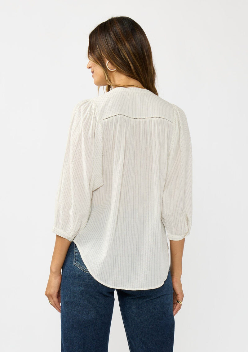 [Color: Cream/Black] A back facing image of a brunette model wearing a boho striped button front blouse with a pintuck yoke, lattice trim, and voluminous sleeves. 