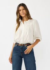 [Color: Cream/Black] A front facing image of a brunette model wearing a boho striped button front blouse with a pintuck yoke, lattice trim, and voluminous sleeves. 