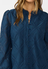 [Color: Navy] A detail image of a brunette model wearing a navy blue button up blouse with a diamond lattice pattern and long sleeves with button cuffs. A versatile top for the office and weekend casual outings. 