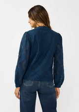 [Color: Navy] A back facing image of a brunette model wearing a navy blue button up blouse with a diamond lattice pattern and long sleeves with button cuffs. A versatile top for the office and weekend casual outings. 