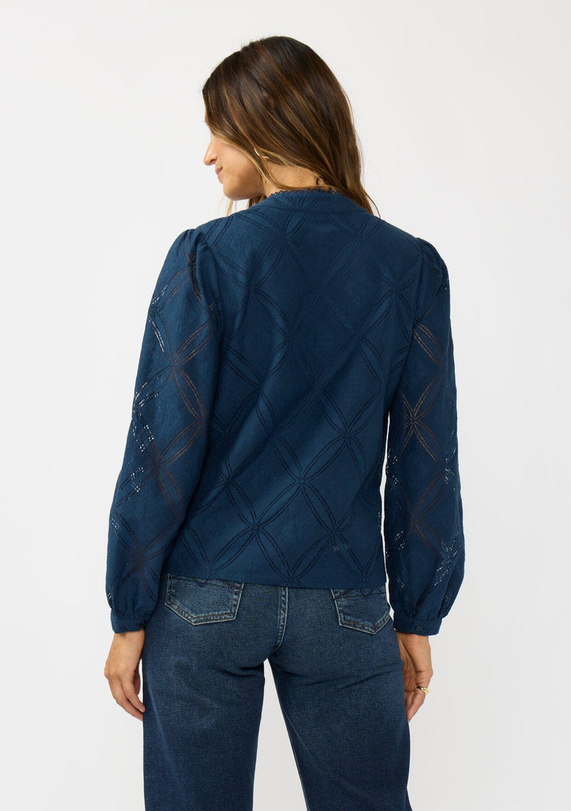 [Color: Navy] A back facing image of a brunette model wearing a navy blue button up blouse with a diamond lattice pattern and long sleeves with button cuffs. A versatile top for the office and weekend casual outings. 