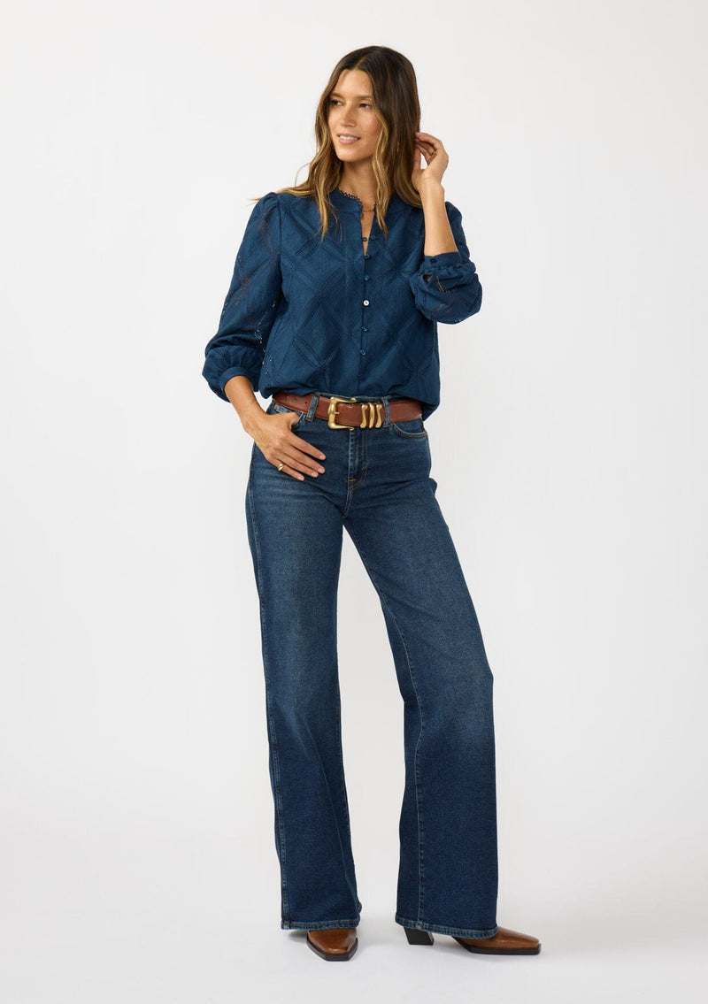 [Color: Navy] A front facing image of a brunette model wearing a navy blue button up blouse with a diamond lattice pattern and long sleeves with button cuffs. A versatile top for the office and weekend casual outings. 