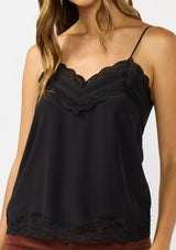 [Color: Black] A detail image of a brunette model wearing a black cami with lace trims on the neck and hem, adjustable spaghetti straps, and a v-neckline. 