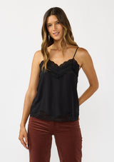 [Color: Black] A front facing image of a brunette model wearing a black cami with lace trims on the neck and hem, adjustable spaghetti straps, and a v-neckline. 