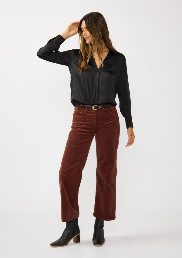 [Color: Black] A front facing image of a brunette model wearing a silky poly satin blouse with a split v-neckline, collar, and long sleeves with button cuffs. 