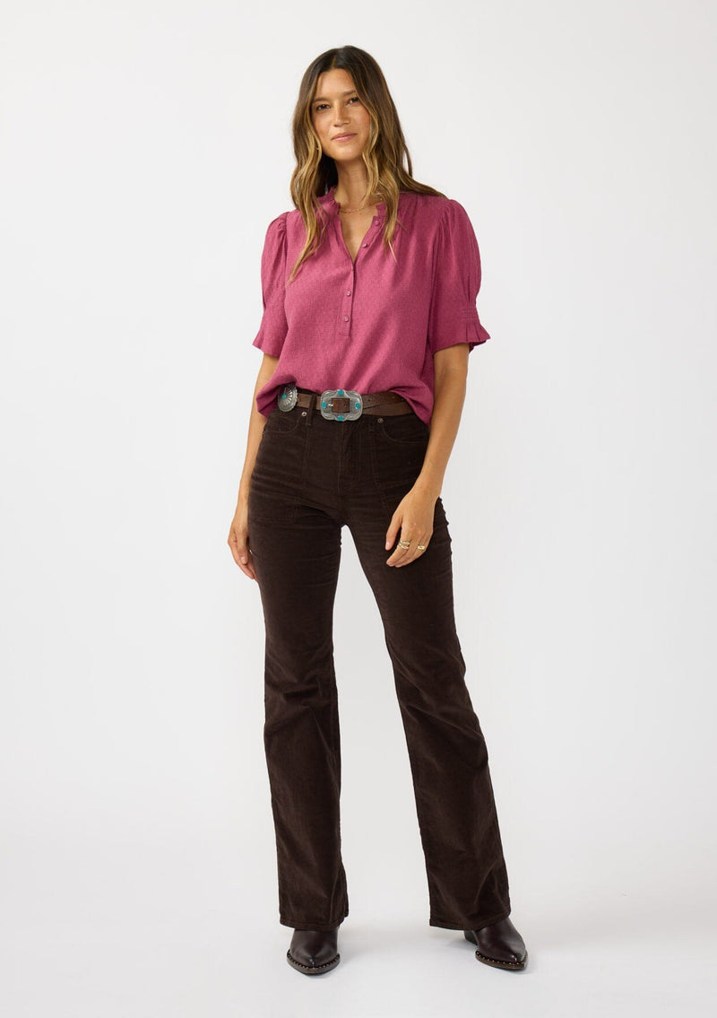 [Color: Berry] A front facing image of a brunette model wearing a pink puff sleeve top with gold metallic threads, a smocked detail on sleeve, and a button front. 