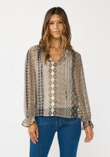 [Color: Natural/Navy] A front facing image of a brunette model wearing a beige striped floral pattern blouse with a relaxed boho silhouette, split v-neckline with ties, and long sleeves with ruffled elastic cuffs. 