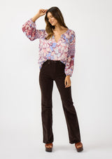 [Color: Natural/Dusty Blue] A front facing image of a brunette model wearing a pink and blue floral chiffon blouse with smocking on the neck and sleeve, and a split v-neckline with button closure. A standout flowy top for the fall season. 