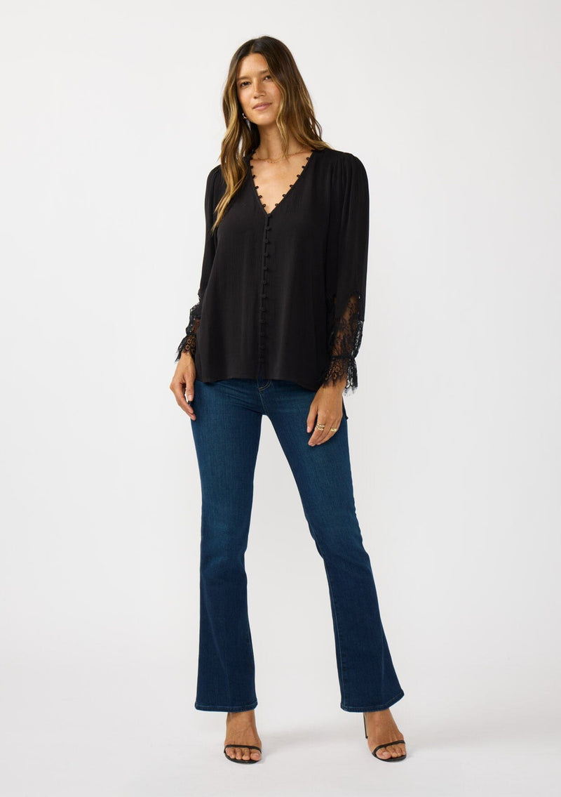 [Color: Black] A front facing image of a brunette model wearing a solid black blouse with lace accented sleeves, button front, and v-neckline. A classic and versatile boho blouse with an elevated touch. 