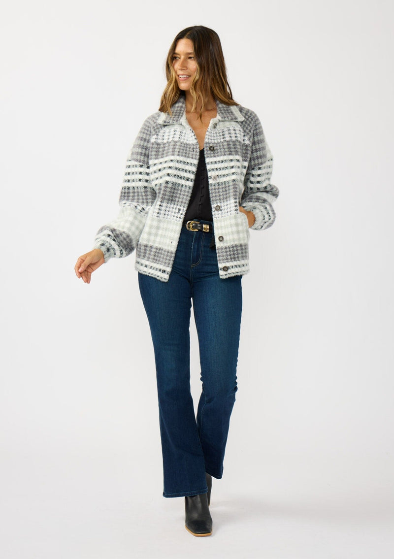 [Color: Grey/Cream] A front facing image of a brunette model wearing a soft and fuzzy grey plaid bomber jacket with a collared neckline, button front, and side pockets. 