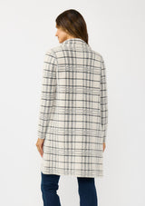 [Color: Cream/Black] A back facing image of a brunette model wearing a fuzzy statement sweater coat in a cream and black plaid print. With long sleeves, a notched collar, a snap button front, and side patch pockets. 
