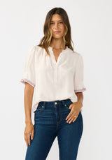 [Color: Pale Rose] A front facing image of a brunette model wearing a light pink pink top with embroidered details on the puff sleeves, a button front, and a ruffled neck accent. 