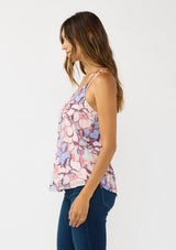 [Color: Natural/Dusty Blue] A side facing image of a brunette model wearing a pink and blue floral tank top with a tie back and racerback detail. A flowy chiffon top for the fall season. 