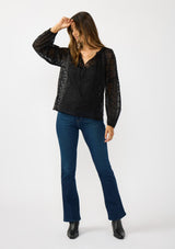 [Color: Black] A front facing image of a brunette model wearing a sheer crinkled chiffon blouse with all over embroidery. Featuring a split v-neckline with tie detail and a button front closure. 