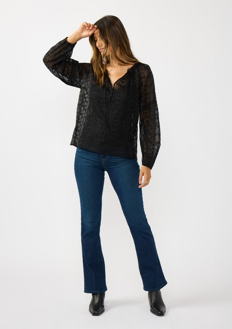 [Color: Black] A front facing image of a brunette model wearing a sheer crinkled chiffon blouse with all over embroidery. Featuring a split v-neckline with tie detail and a button front closure. 