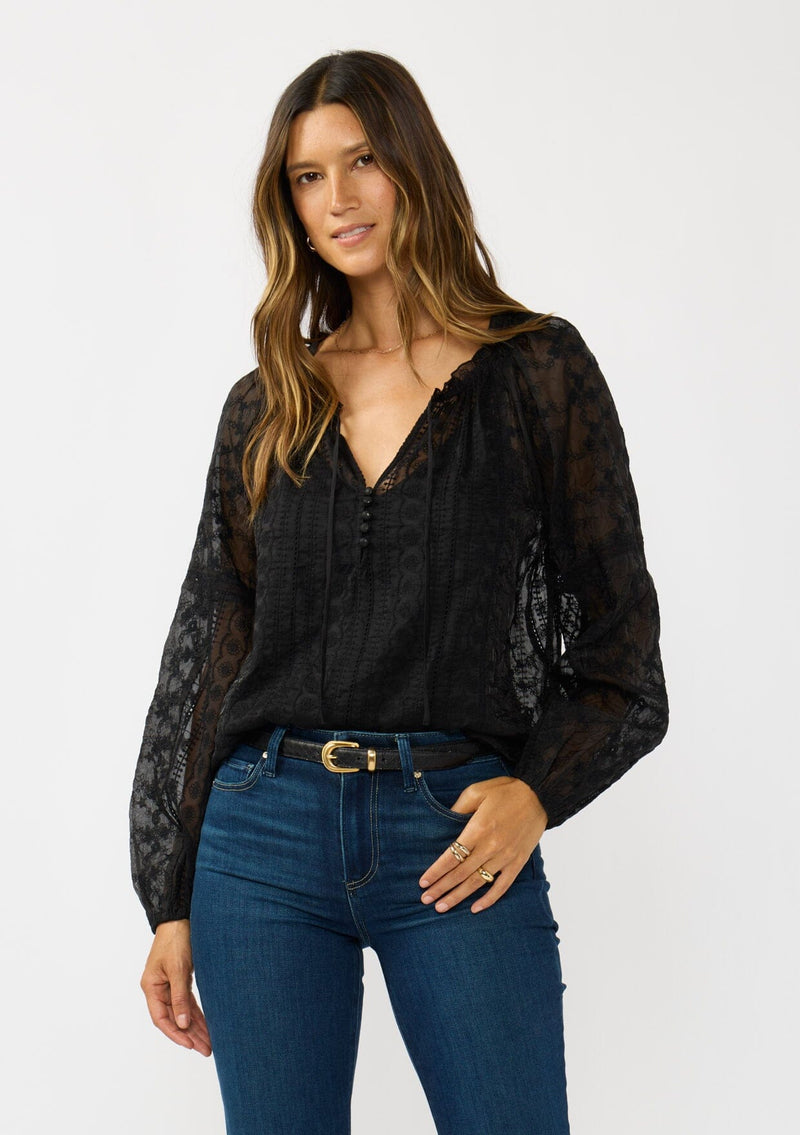 [Color: Black] A front facing image of a brunette model wearing a sheer crinkled chiffon blouse with all over embroidery. Featuring a split v-neckline with tie detail and a button front closure. 