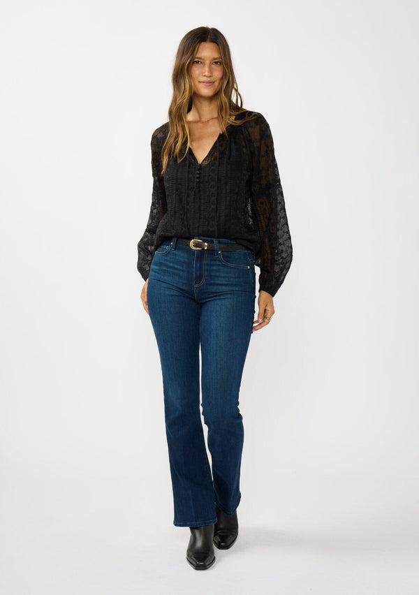 [Color: Black] A front facing image of a brunette model wearing a sheer crinkled chiffon blouse with all over embroidery. Featuring a split v-neckline with tie detail and a button front closure. 